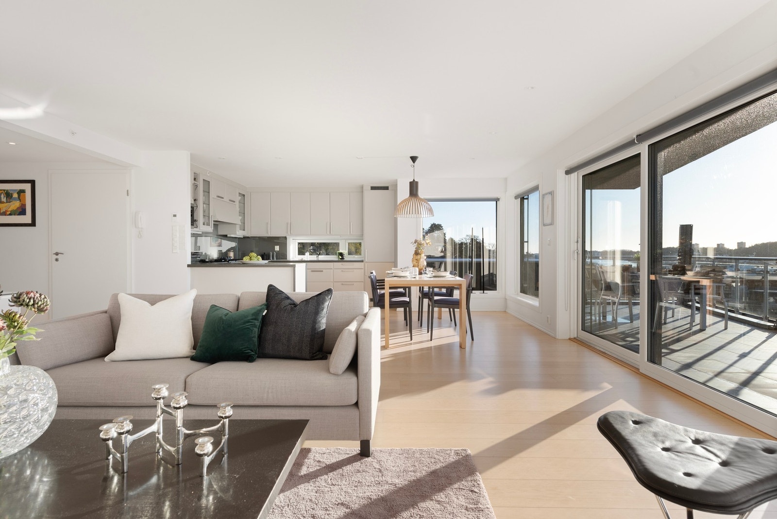 Her kommer du inn i stue og kjøkken i åpen løsning - store vindusflater slipper inn rikelig med lys og fremhever den romslige og åpne atmosfæren Galleribilde