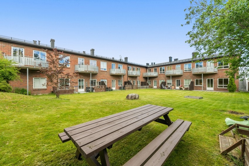 Felles hage, nesten som et atrium, med gode plenarealer, omkranset av bygningsmassen på to sider, samt trær og høye levegger langs tomtegrensen. Galleribilde