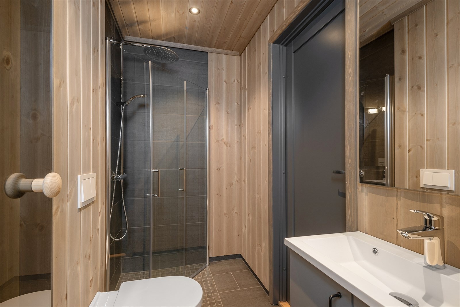 Også dette badet har fliser på gulv og i dusjsonen. Innfellbare glassdører i dusjen. Servantinnredningen har skap for oppbevaring. Vegghengt WC. Galleribilde