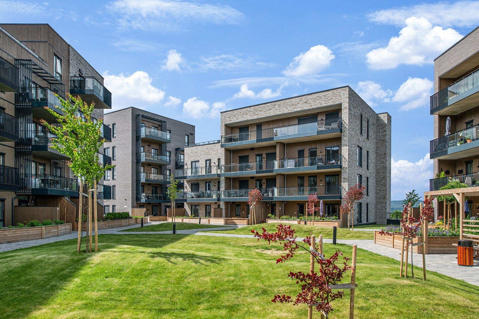 Atriet er gjennomført med steinlagte gangveier, plen, fine sittebenker og lekeplass. Galleribilde