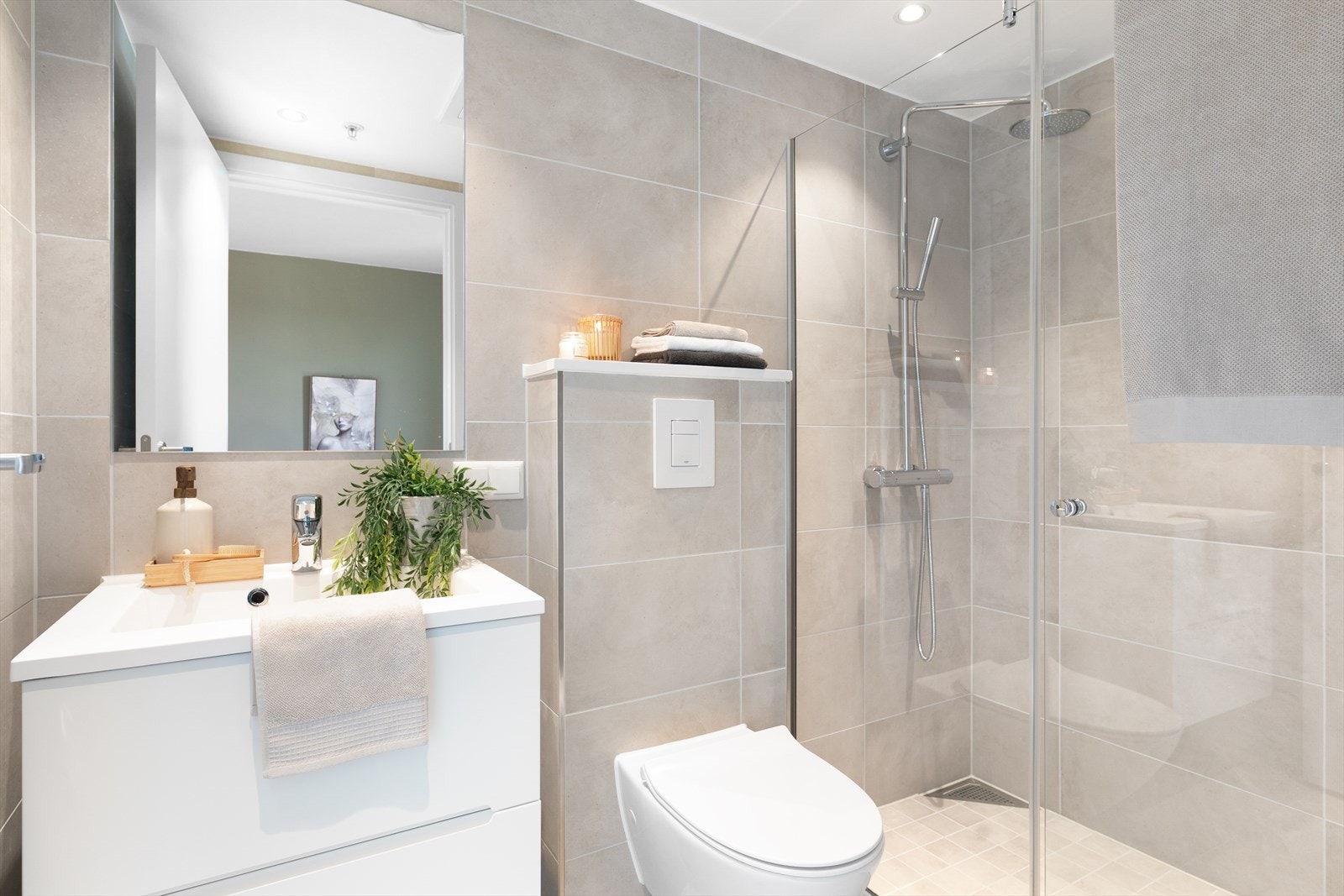 Delikat bad med jordfargede fliser på gulv og vegger, hvit baderomsinnredning som gir en fin kontrast. Galleribilde