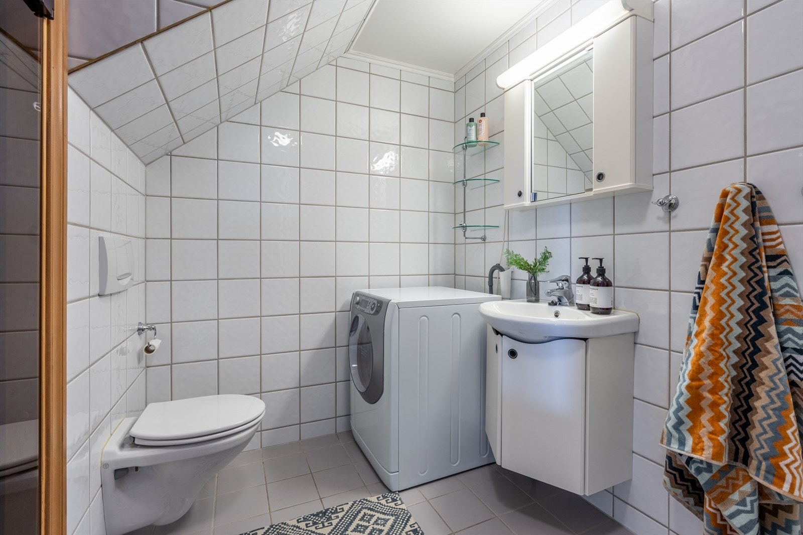 Baderom med fliser på gulv og vegger. Opplegg for vaskemaskin. Galleribilde