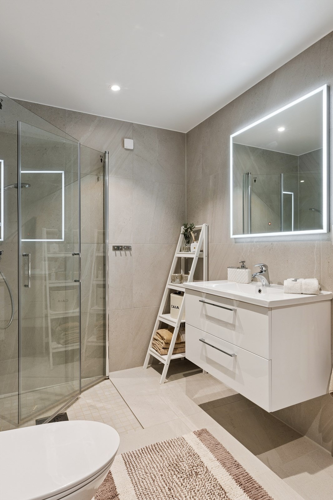 Det andre badet ligger i underetasjen, lett tilgjengelig fra de tre soverommene. Også her er det lagt vekt på moderne materialvalg, lyse detaljer og god plass, med dusjløsning og innredning som dekker familiens behov. Galleribilde