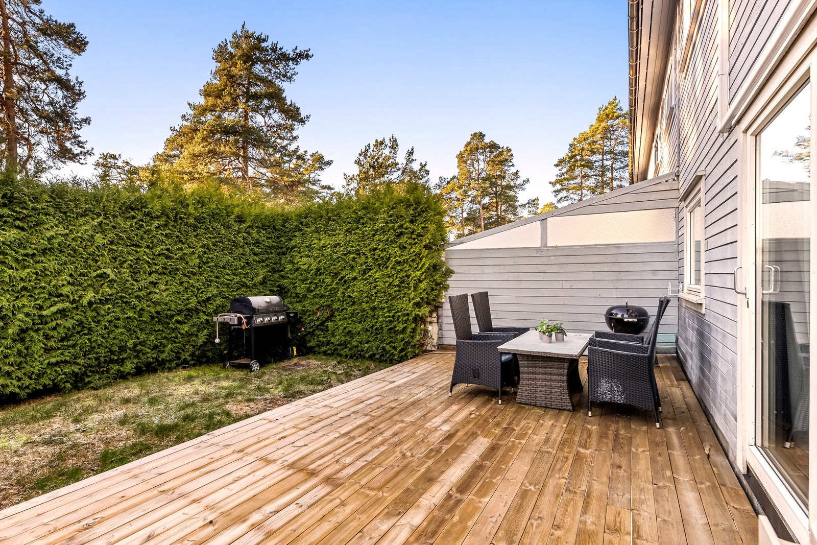 En stor tujahekk bidrar til lite innsyn og lun stemning. Galleribilde