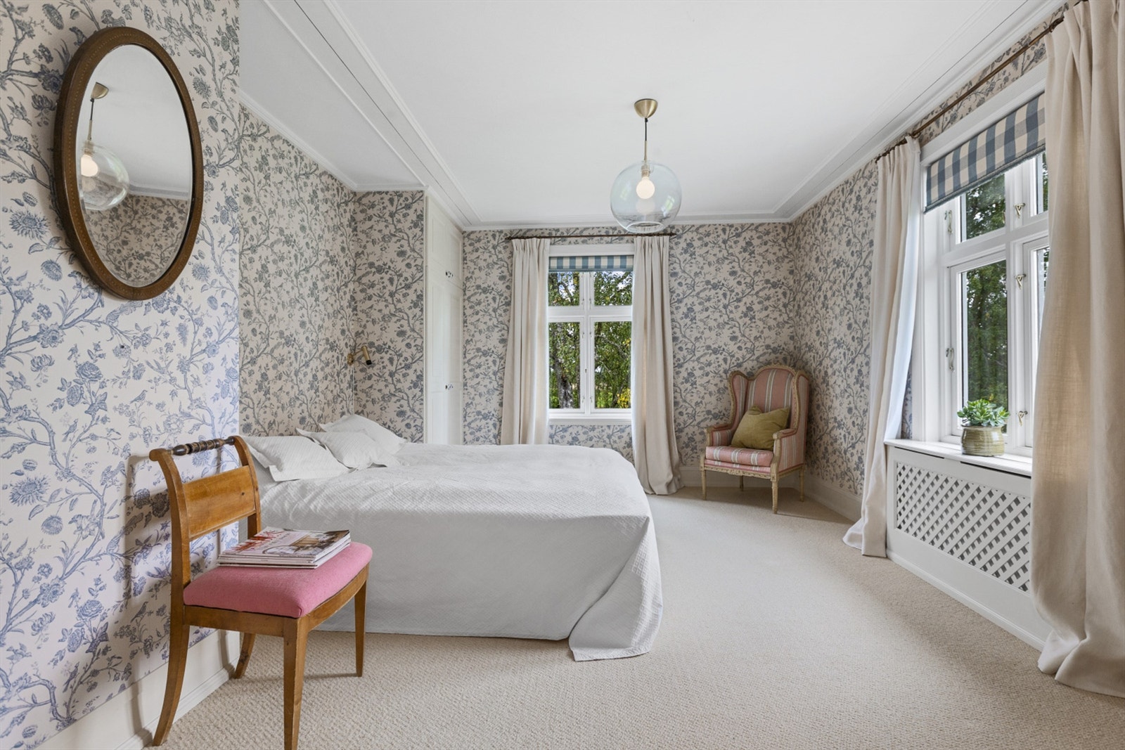 Soverom med en lyseblå og mønstret tapet med et lyst og lunt vegg til gulv teppe. Galleribilde