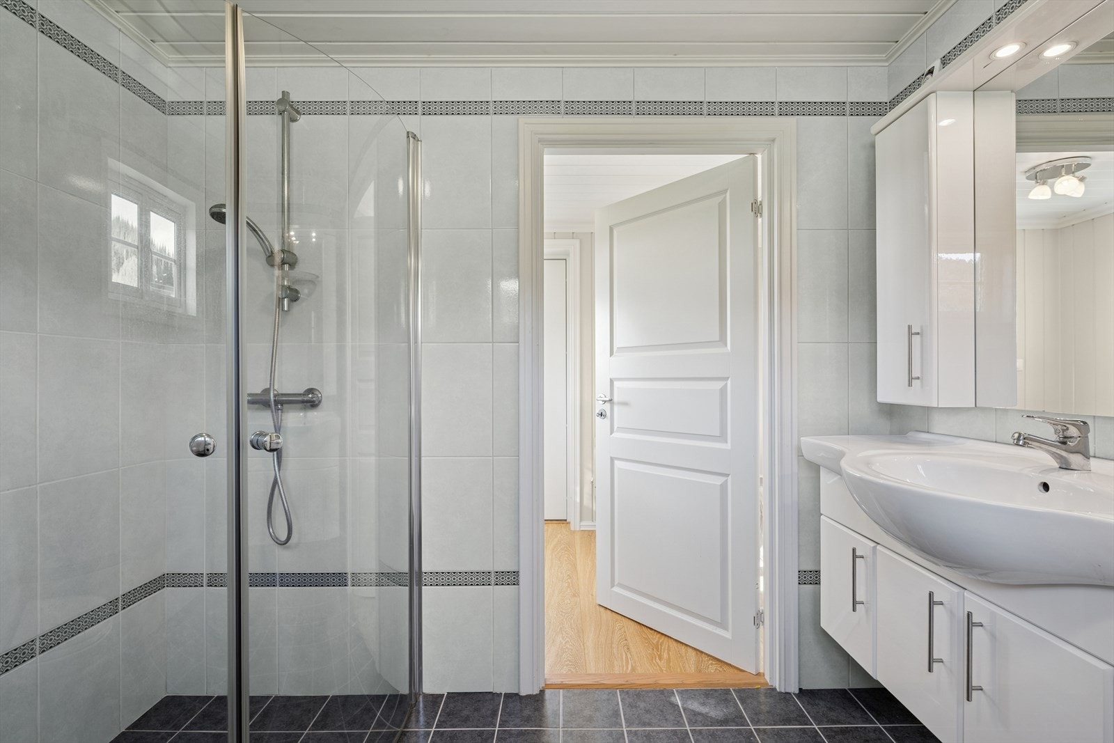 Baderommet innehar frittstående toalett, servantskap, dusjhjørnet og opplegg til vaskemaskin. Galleribilde