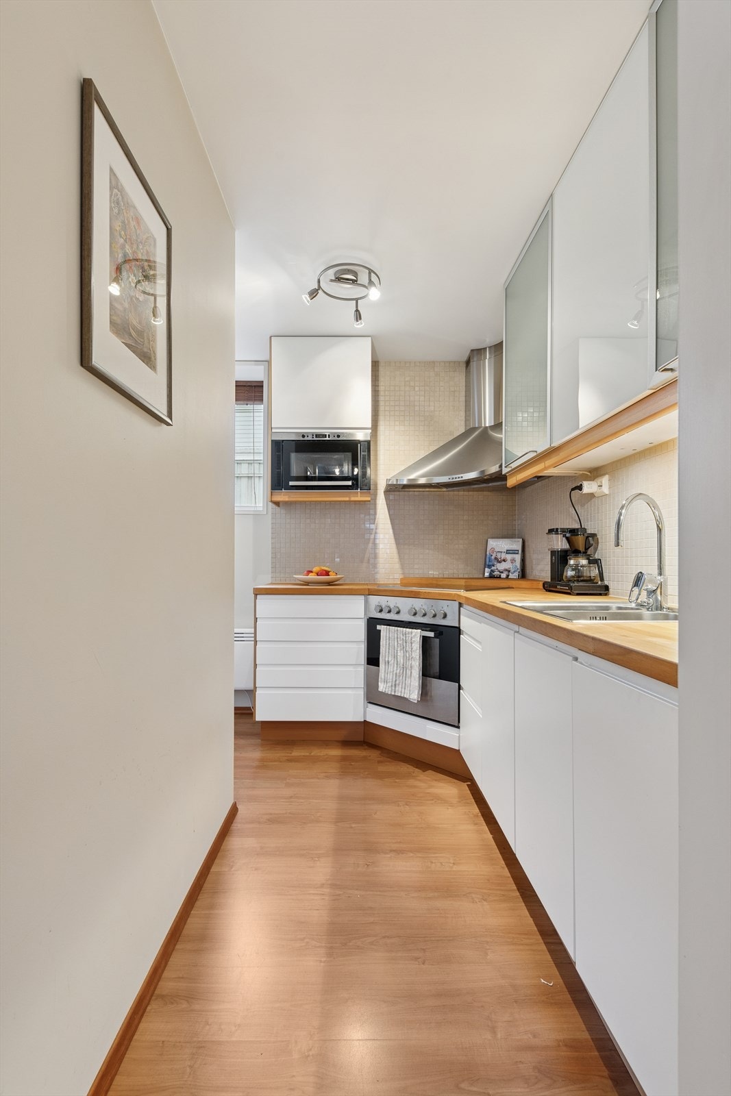 Det har lyse, slette fronter, lys benkeplate og integrerte hvitevarer som kjøl/frys, komfyr, platetopp, oppvaskmaskin og mikrobølgeovn - alt dette medfølger handelen. Galleribilde