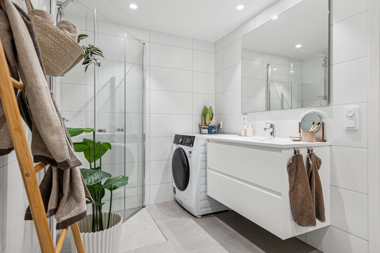 Delikat baderom utstyrt med servantinnredning, vegghengt toalett og dusjhjørne, samt opplegg for vaskemaskin. Galleribilde