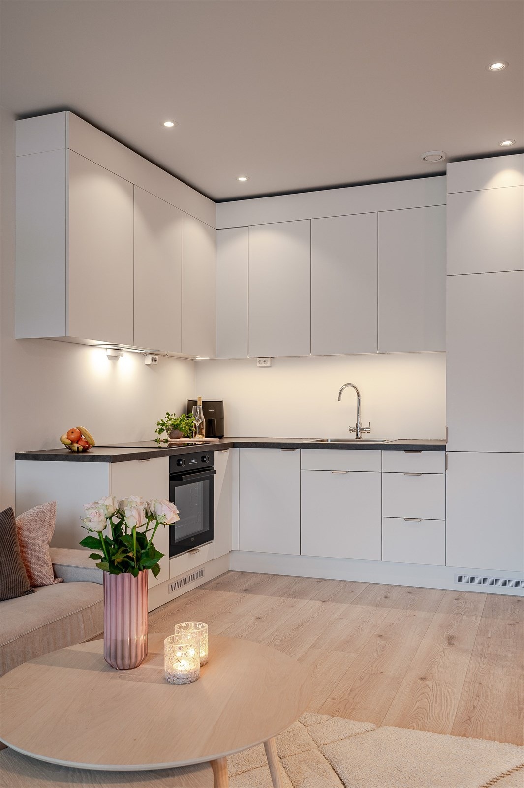 Hvite, glatte kjøkkenfronter og mørk benkeplate gir et rent og ryddig inntrykk. Galleribilde