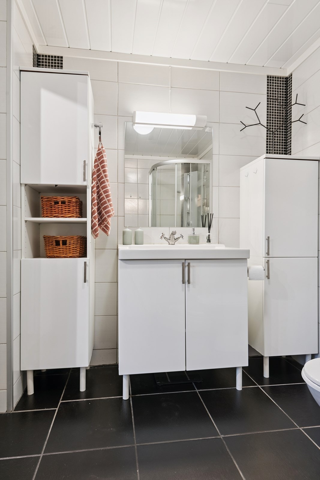 Badet er innredet med servant, høyskap for oppbevaring og flislagte overflater. Galleribilde