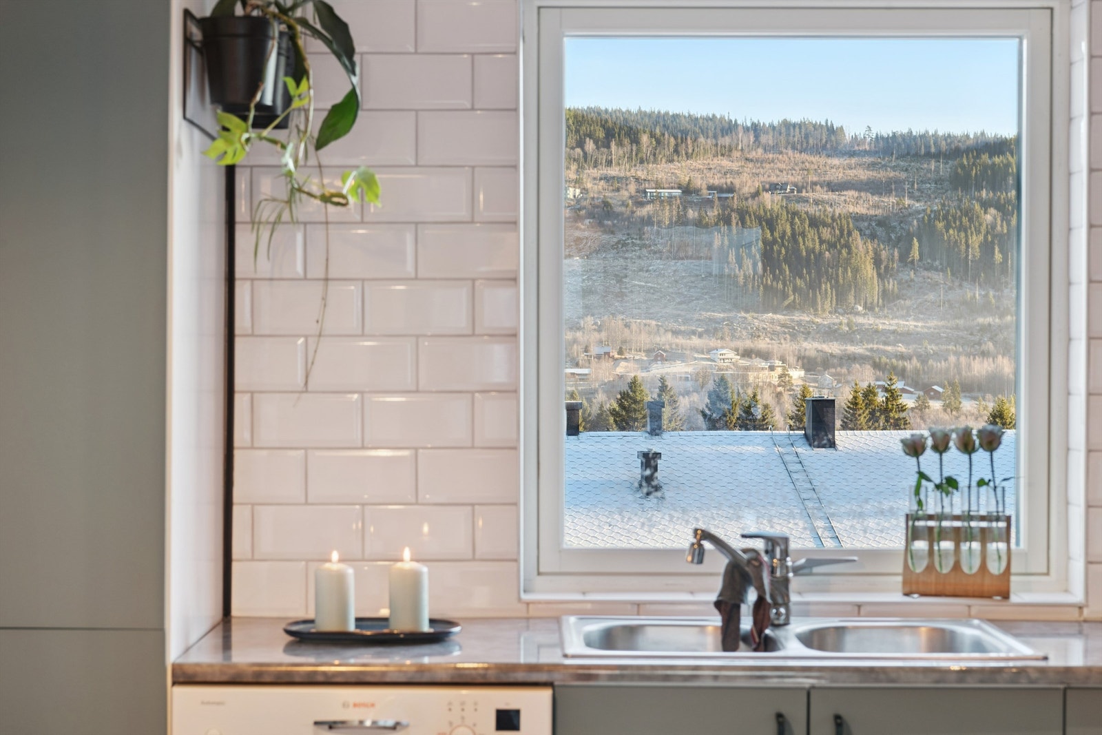 Flislagt vegg over laminatbenkeplaten og en dobbel oppvaskkum i metall. Galleribilde