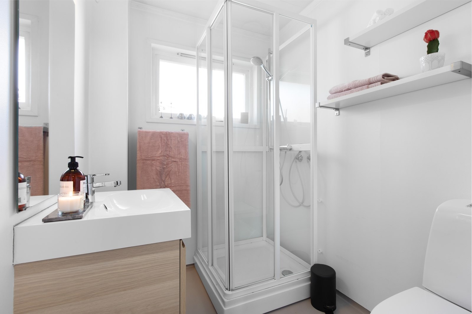 Lyst og nøytralt bad innredet med dusjkabinett, WC og servant med skap under. Galleribilde