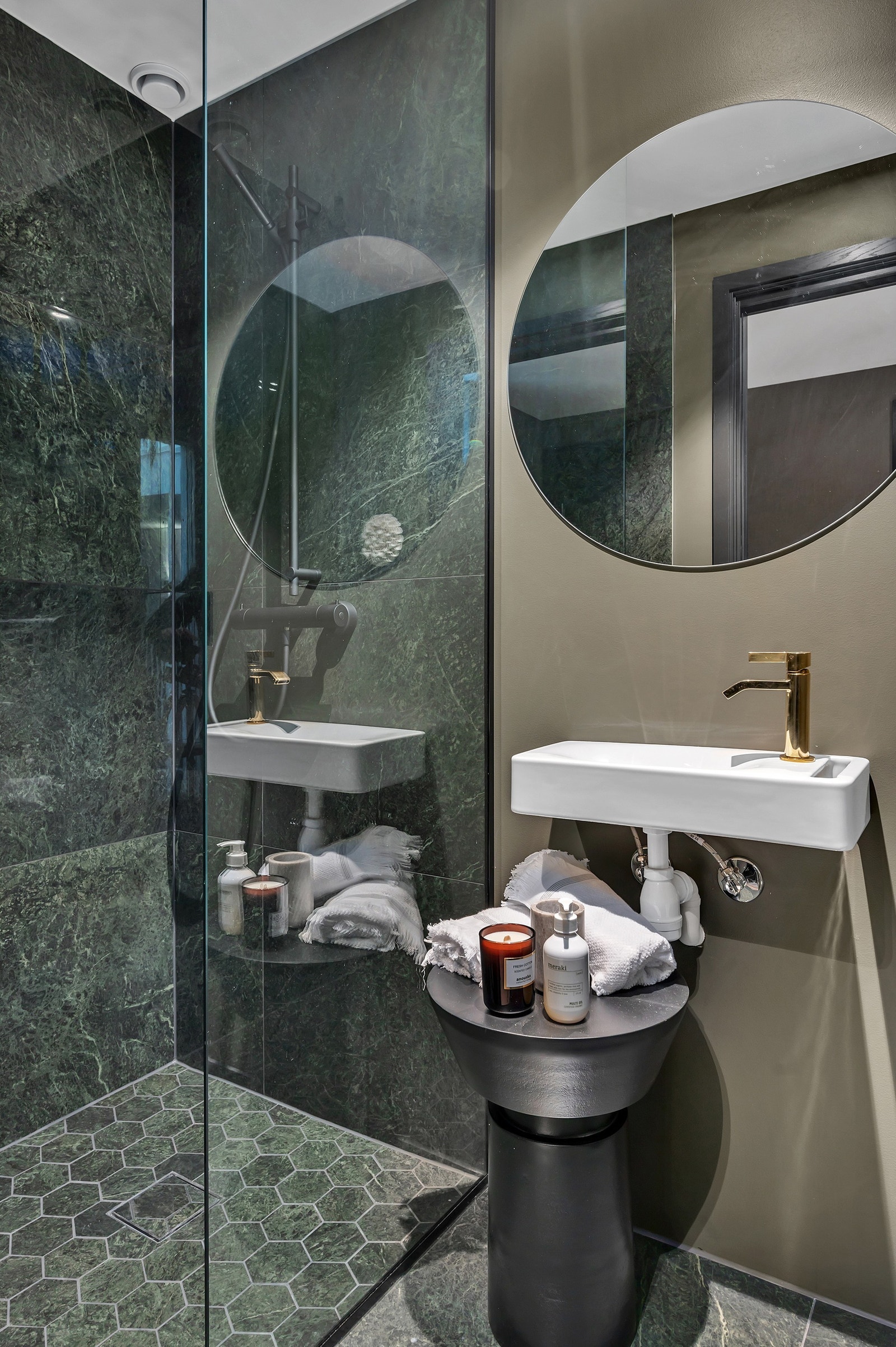 Badet har moderne mørke fliser med dusjhjørne, vask og toalett. Galleribilde