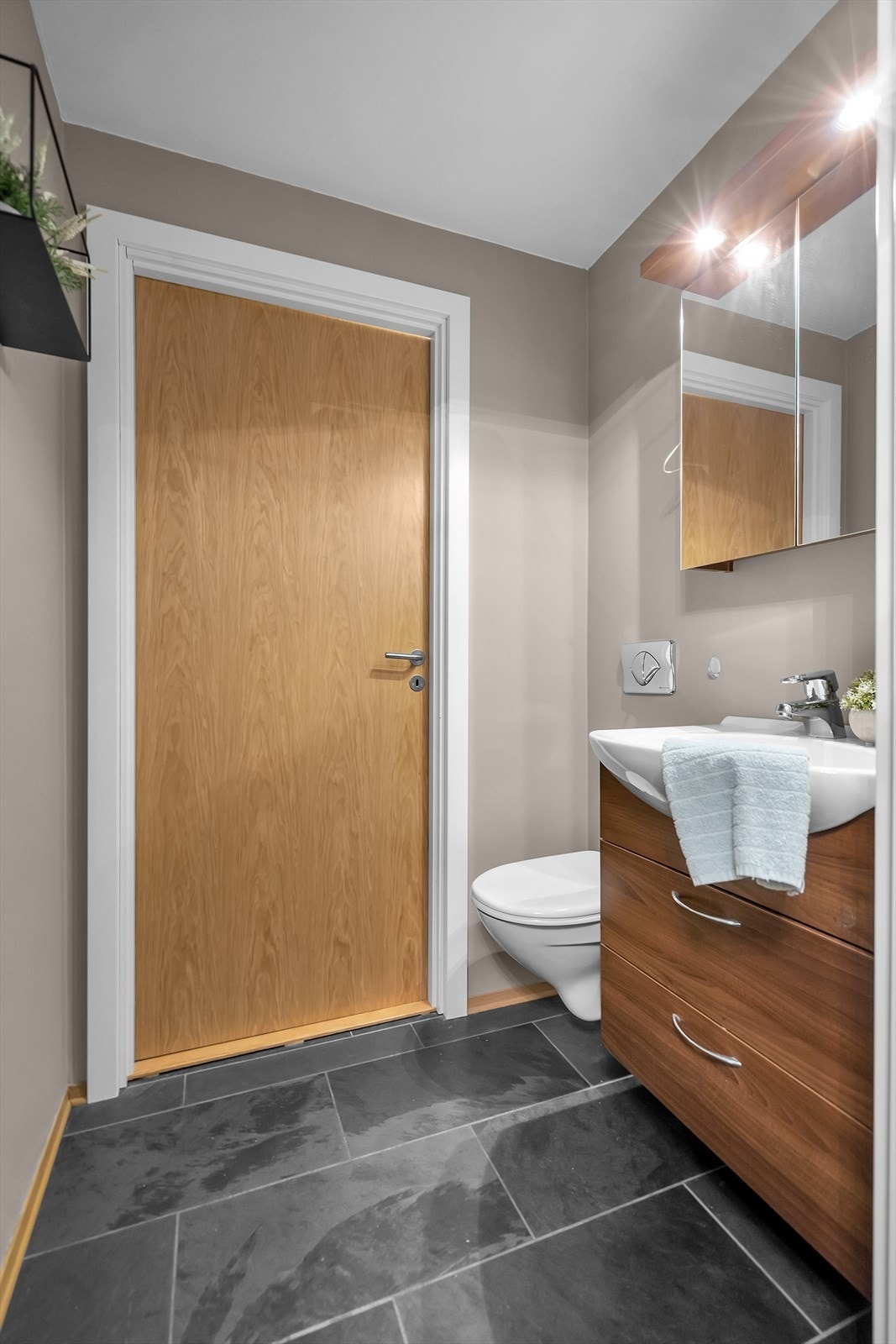 Praktisk og funksjonelt separat toalettrom. Rommet er innredet med speilskap, servant med underskuffer som gir ekstra oppbevaringsmuligheter, samt vegghengt toalett for et moderne uttrykk. Skiferlagt gulv med vannbåren varme. Galleribilde