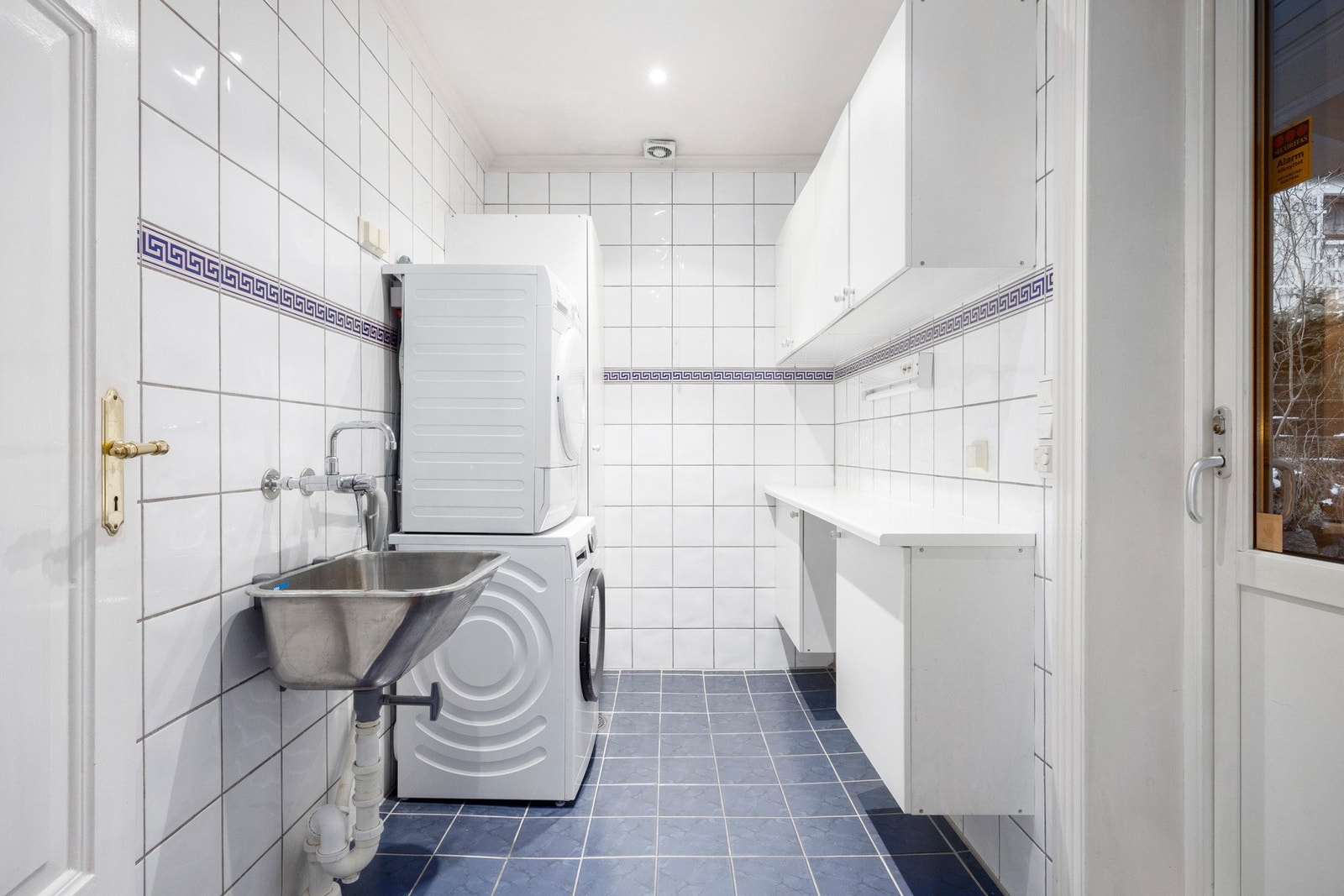 Et romslig og funksjonelt vaskerom med god skapplass, utslagsvask og opplegg for vaskemaskin. Galleribilde