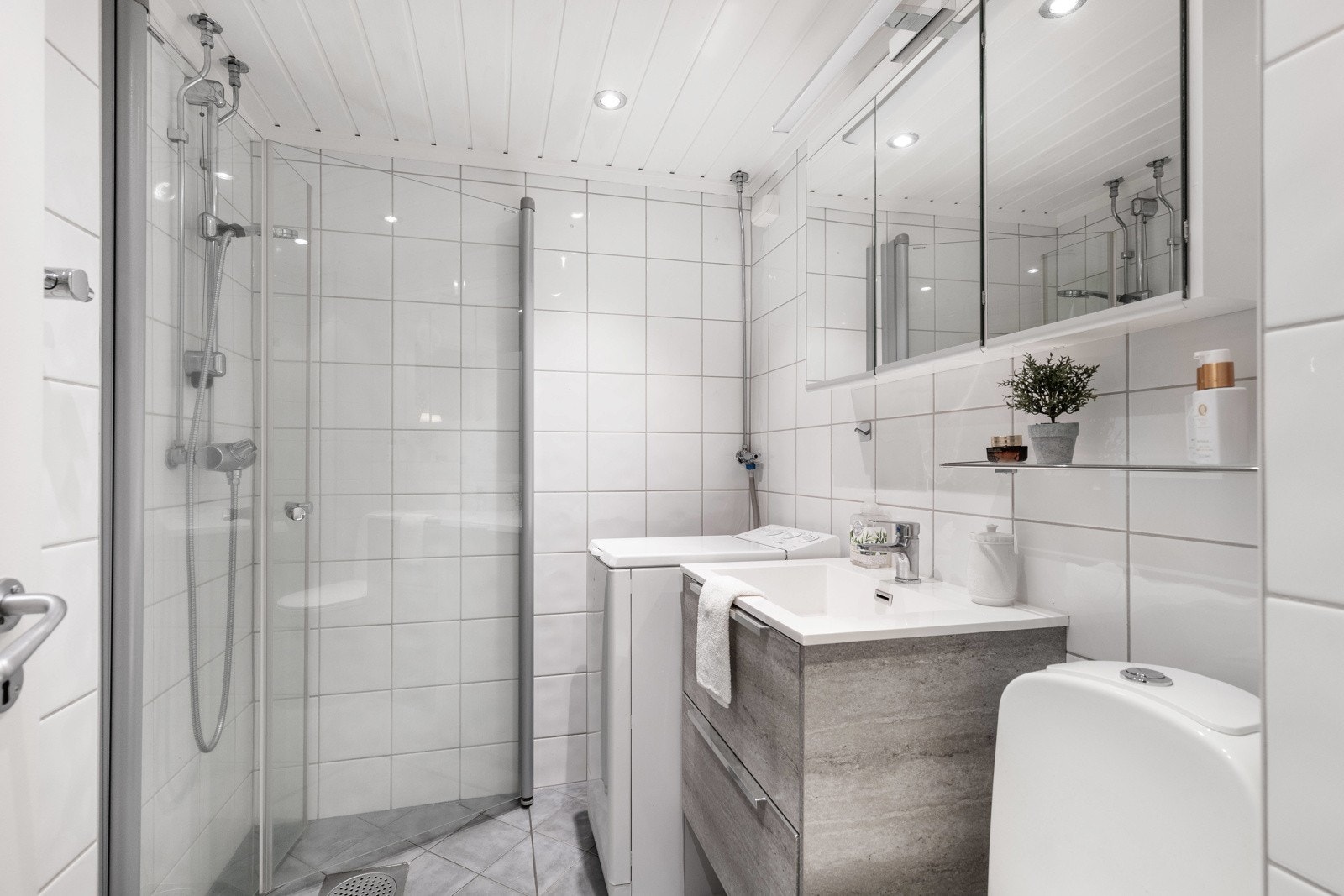 Flislagt bad fra 2009 med dusjhjørne, servant med underskap og plass til vaskemaskin. Galleribilde