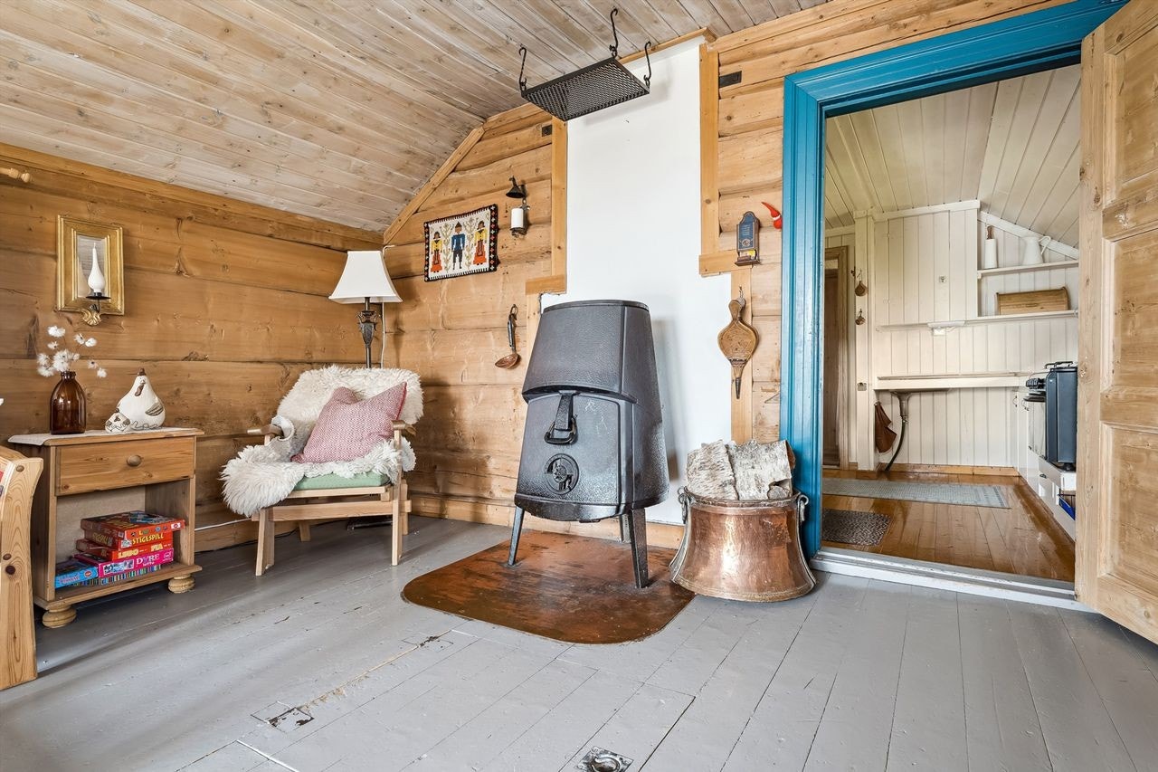 Videre inn kommer du inn i stuen. Stuen har tømmer på veggene og gråmalt tregulv. Galleribilde