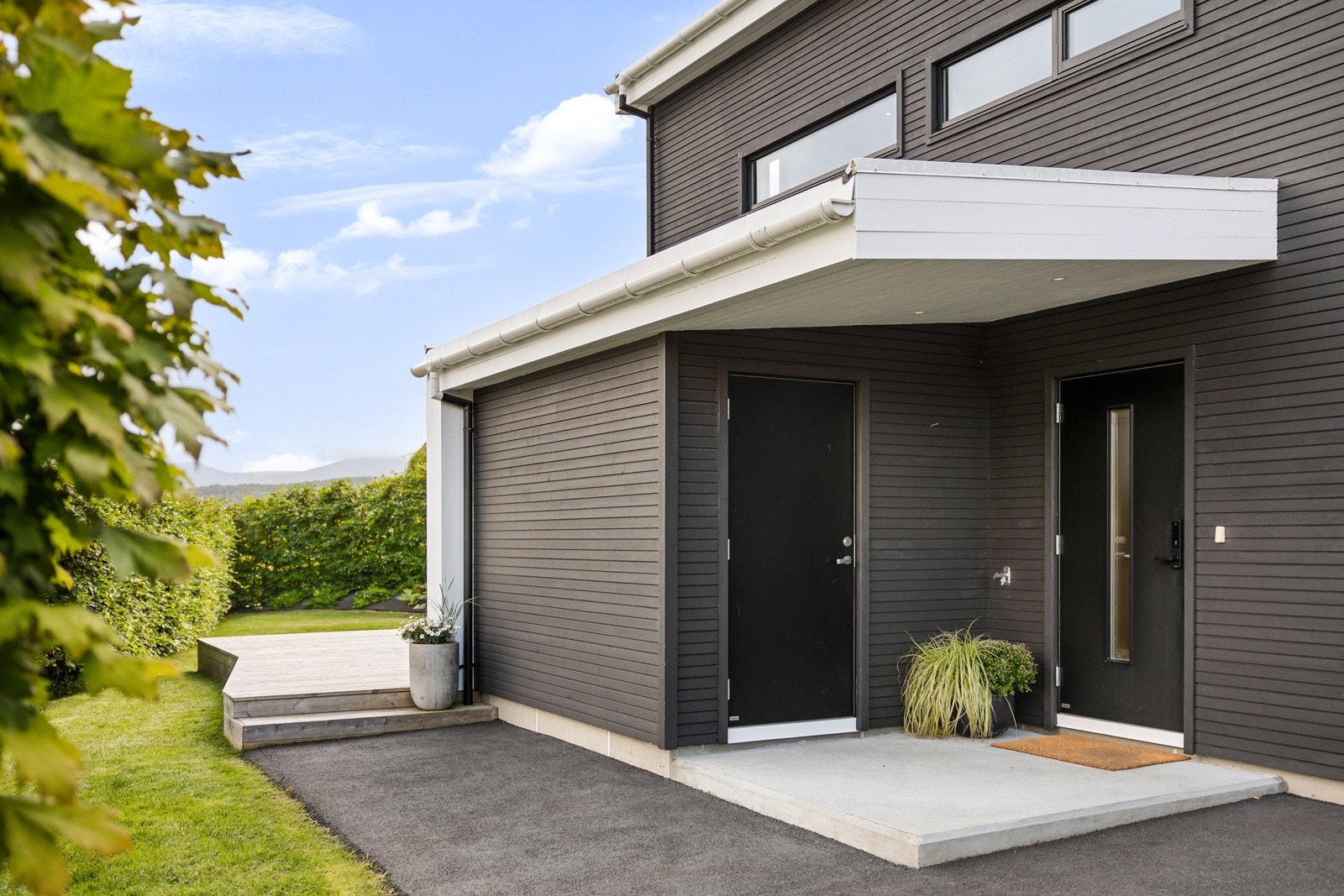 Inngangspartiet er pent opparbeidet med asfaltert innkjørsel og støpt plate foran inngangsdøren. Galleribilde