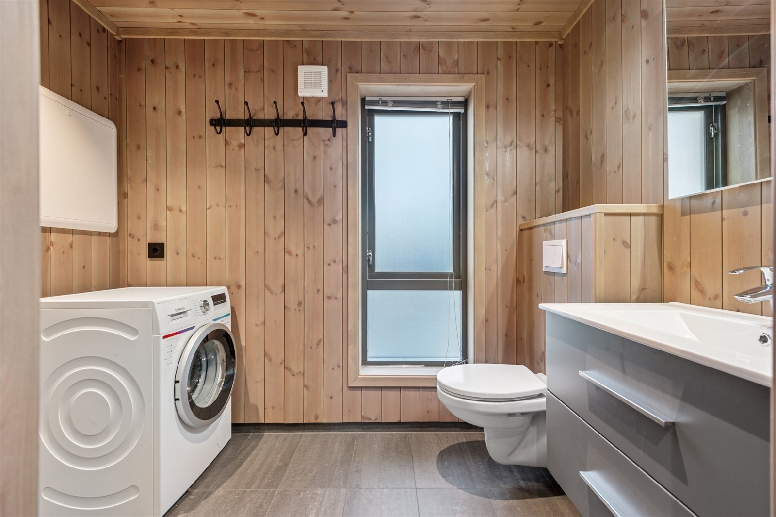 Flislagt bad med gulvvarme, dusj og vegghengt toalett. Galleribilde