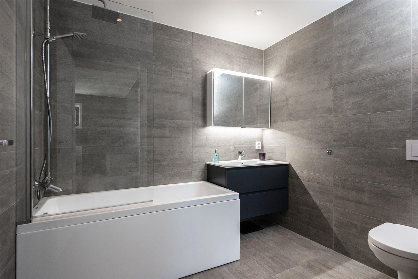 Fliser på vegger og gulv gir et stilrent uttrykk på badet fra 2022. Mekanisk avtrekk i tak sikrer god ventilasjon. Galleribilde