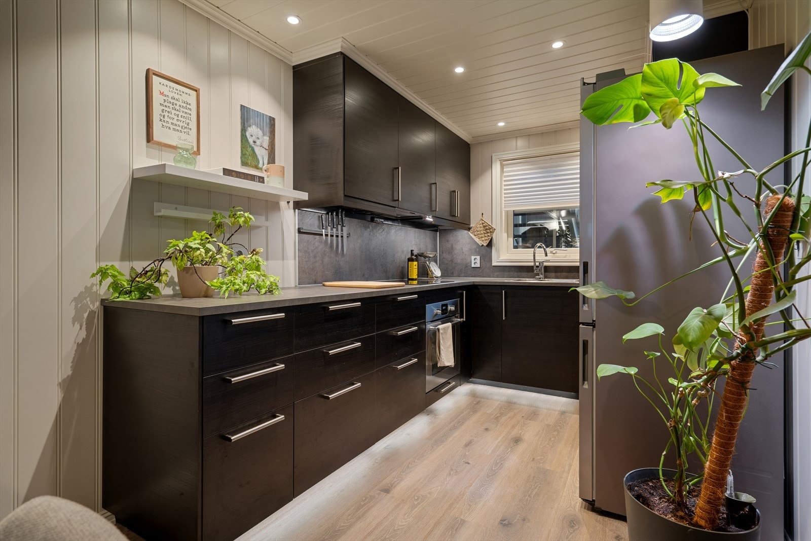 Kjøkkenet fra 2018 har moderne innredning med slette fronter, takhøye overskap og laminatbenkeplate med nedfelt benkebeslag og to kummer. Galleribilde