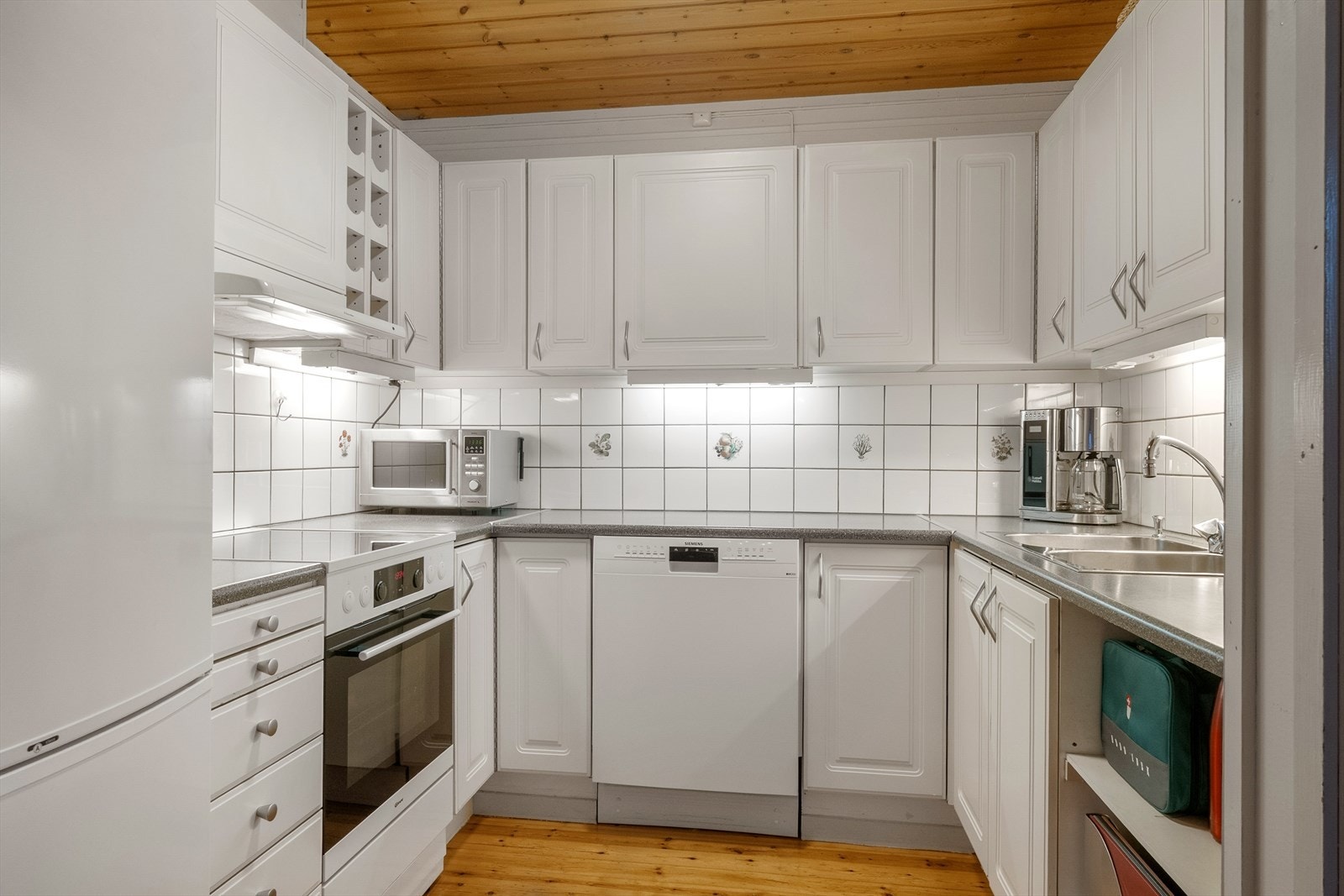 Flislagt vegg og integrert oppvaskmaskin gir et stilrent og praktisk preg. Galleribilde