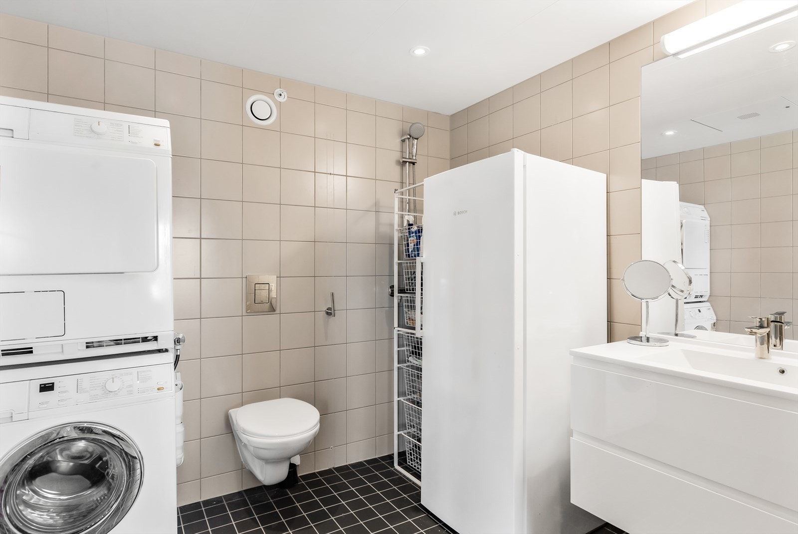 Delikat bad/vaskerom med varmekabler i gulv. Innredet med vegghengt wc, dusjhjørne (dusjvegger demontert), opplegg for vaskemaskin/tørketrommel og moderne baderomsinnredning. Galleribilde