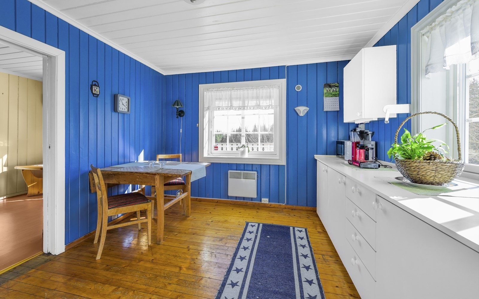 Kjøkken med hvit glatt innredning og frittstående hvitevarer Galleribilde