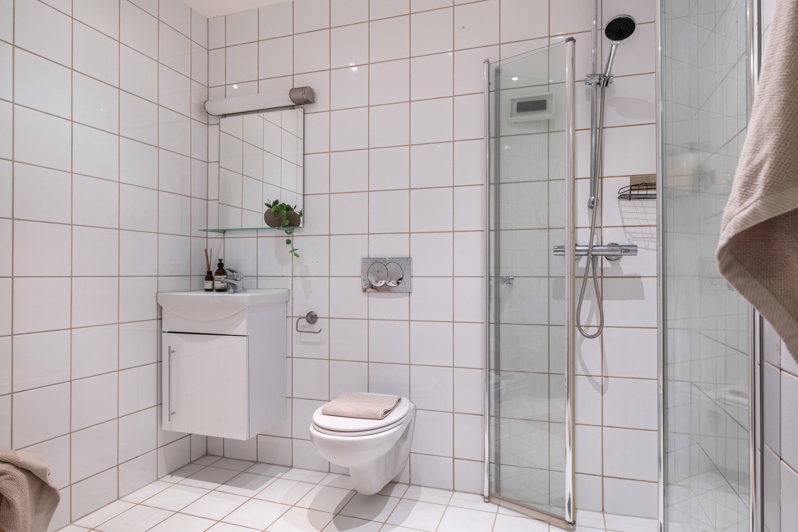 Leiligheten har et lyst flislagt baderom fra 2011. Baderommet er utstyrt med vegghengt servant, speil med glasshylle og belysning over, dusjhjørne med innfellbare glassdører og vegghengt toalett. Galleribilde