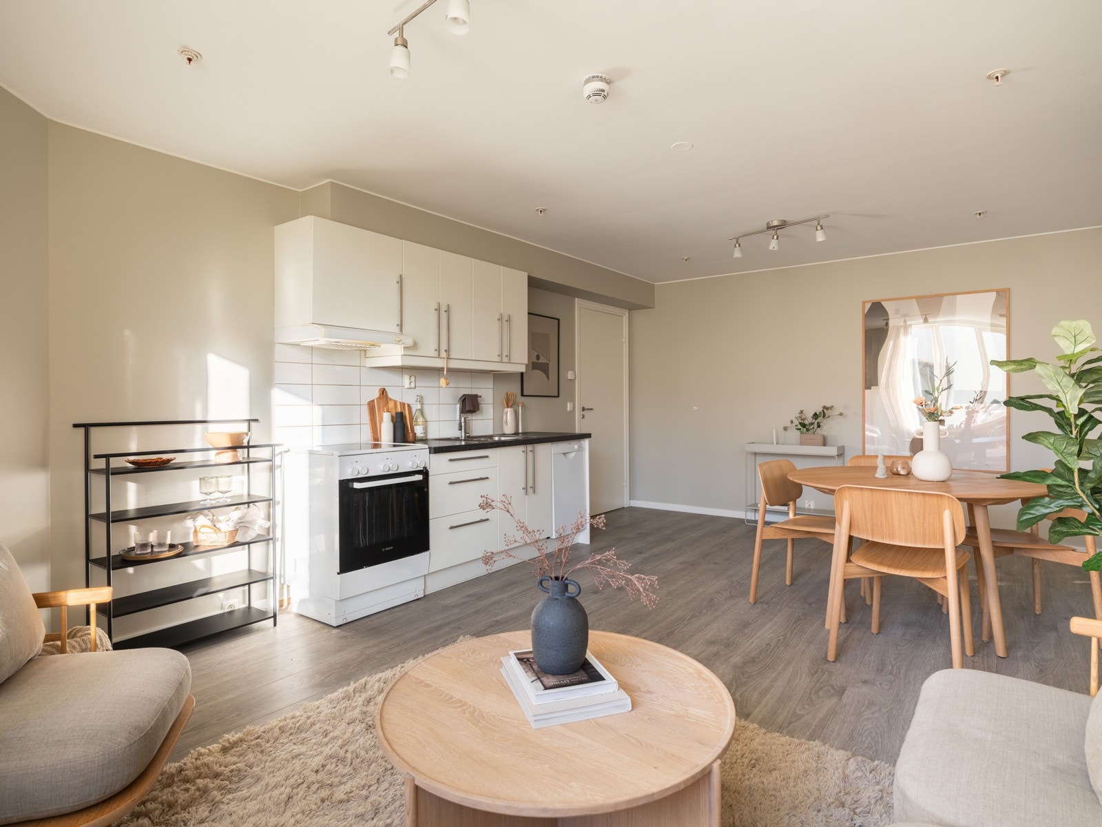 Lys og moderne kjøkkeninnredning fra 2011 med hvite glatte fronter og laminert benkeplate med nedfelt oppvaskkum. Praktisk med lyse fliser i benkeryggen og belysning under overskap. Galleribilde