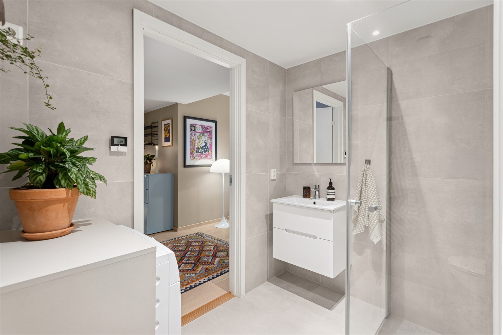 Flislagt baderom (hovedbaderom) fra 2020 med vannbåren gulvvarme og malt himling med downlights. Badet har dusj med innfellbare glassvegger, en heldekkende servant med tilhørende innredning og et vegghengt toalett med skjult sisterne. Galleribilde