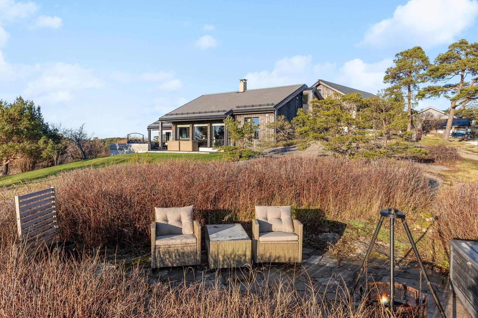 Nedre del av tomta har platting med hekk hvor det er mulighet for å nyte kvelder rundt bålpannen. Galleribilde