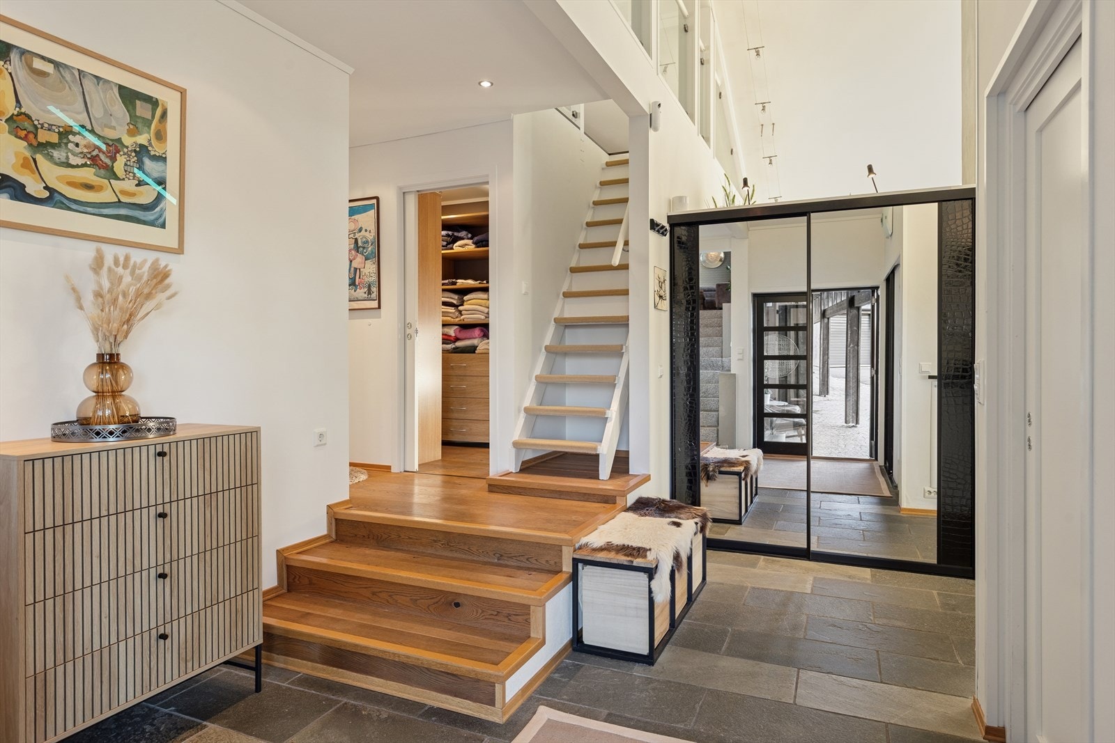 Man ønskes velkommen inn i en romslig entre med flere oppbevaringsmuligheter. Fra stuen/entre er det tilkomst til en koselig hems via heltre trapp og rekkverk av glass. Galleribilde
