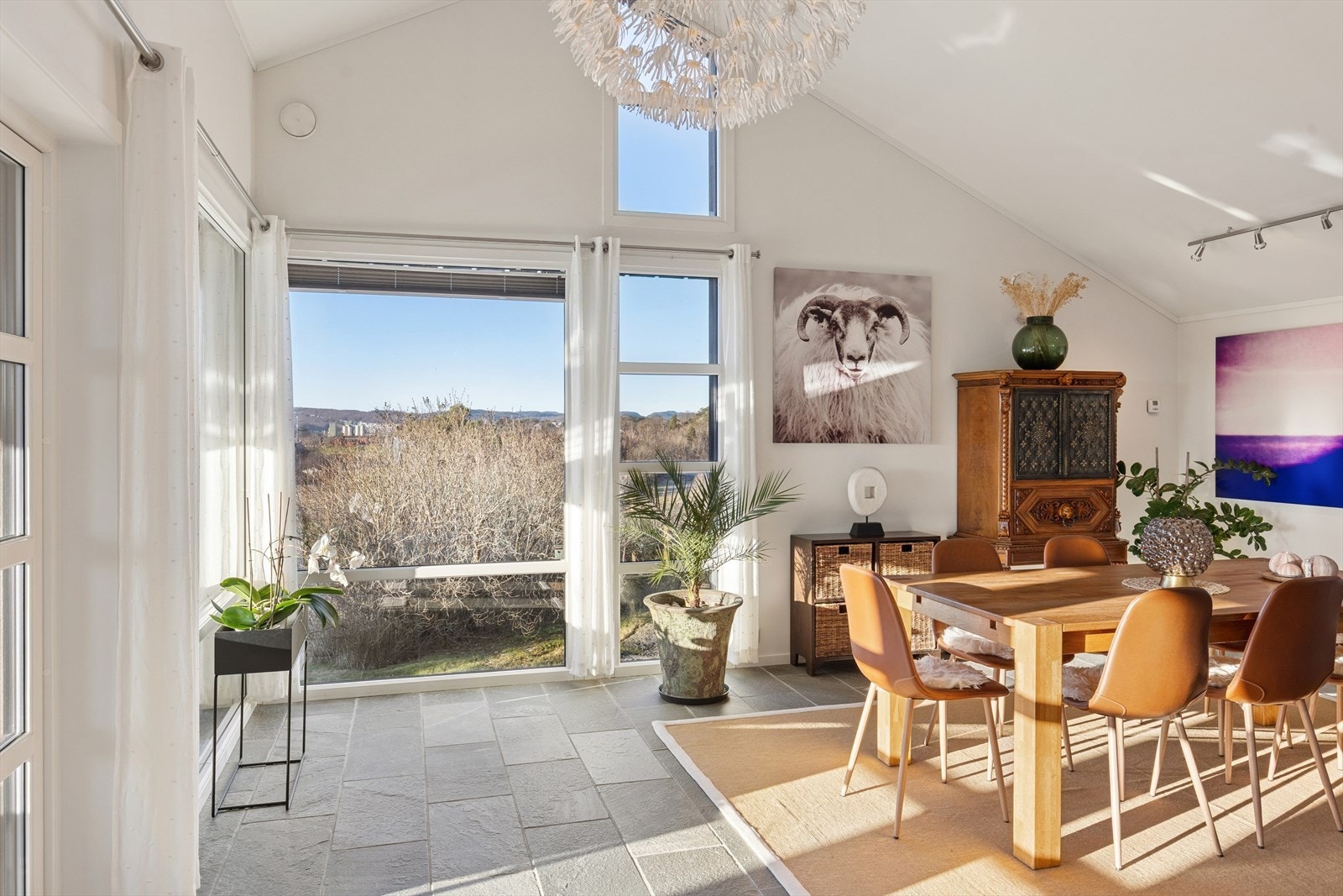 Et stort rom med steingulv og direkte utgang til terrassen og hagen. Galleribilde