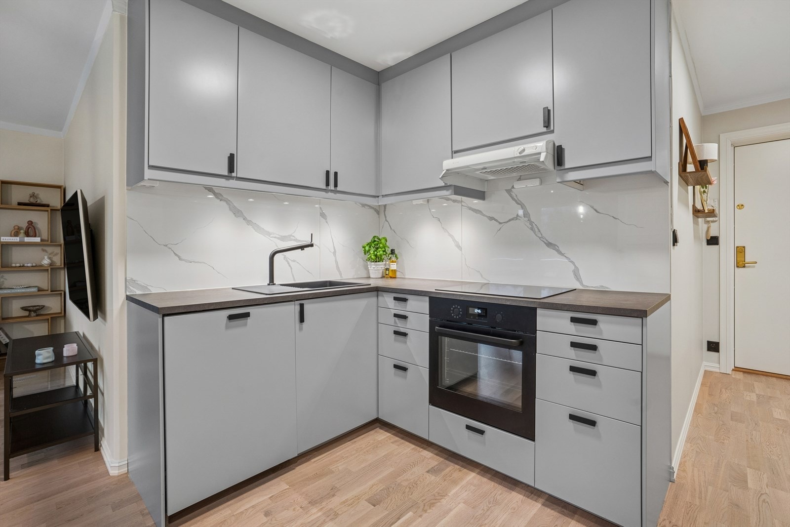 Kjøkkeninnredningen har grå, glatte fronter og sort laminatbenkeplate. Galleribilde