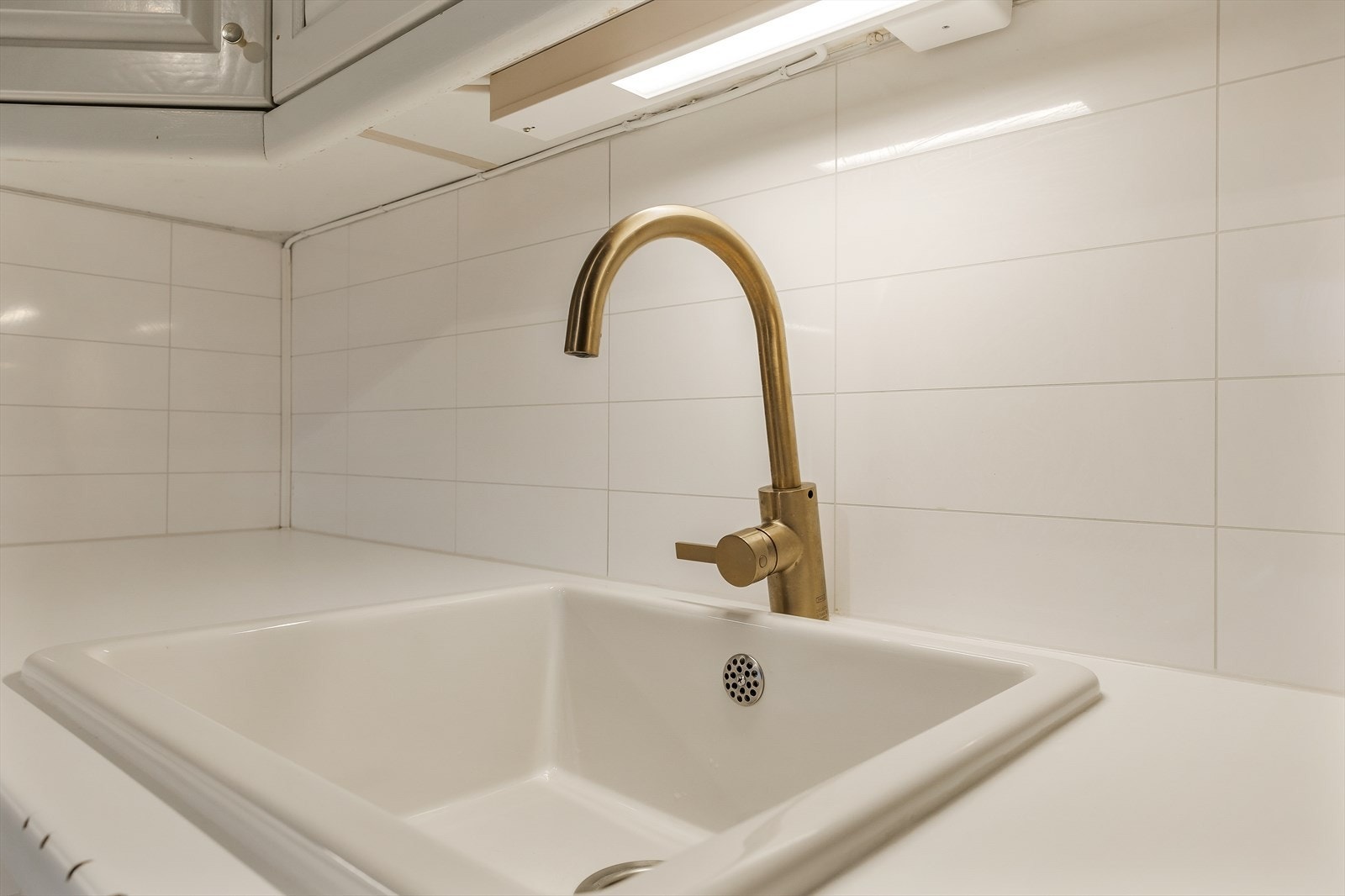 Detaljer som fliser over benk og ett-greps kran i messing-finish. Galleribilde