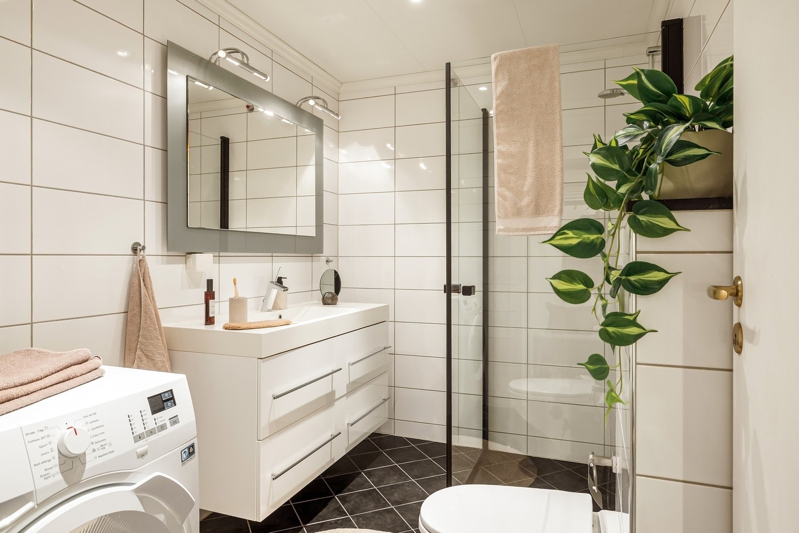 Pent bad innredet med servant, vegghengt toalett, dusjhjørne og opplegg for vaskemaskin Galleribilde