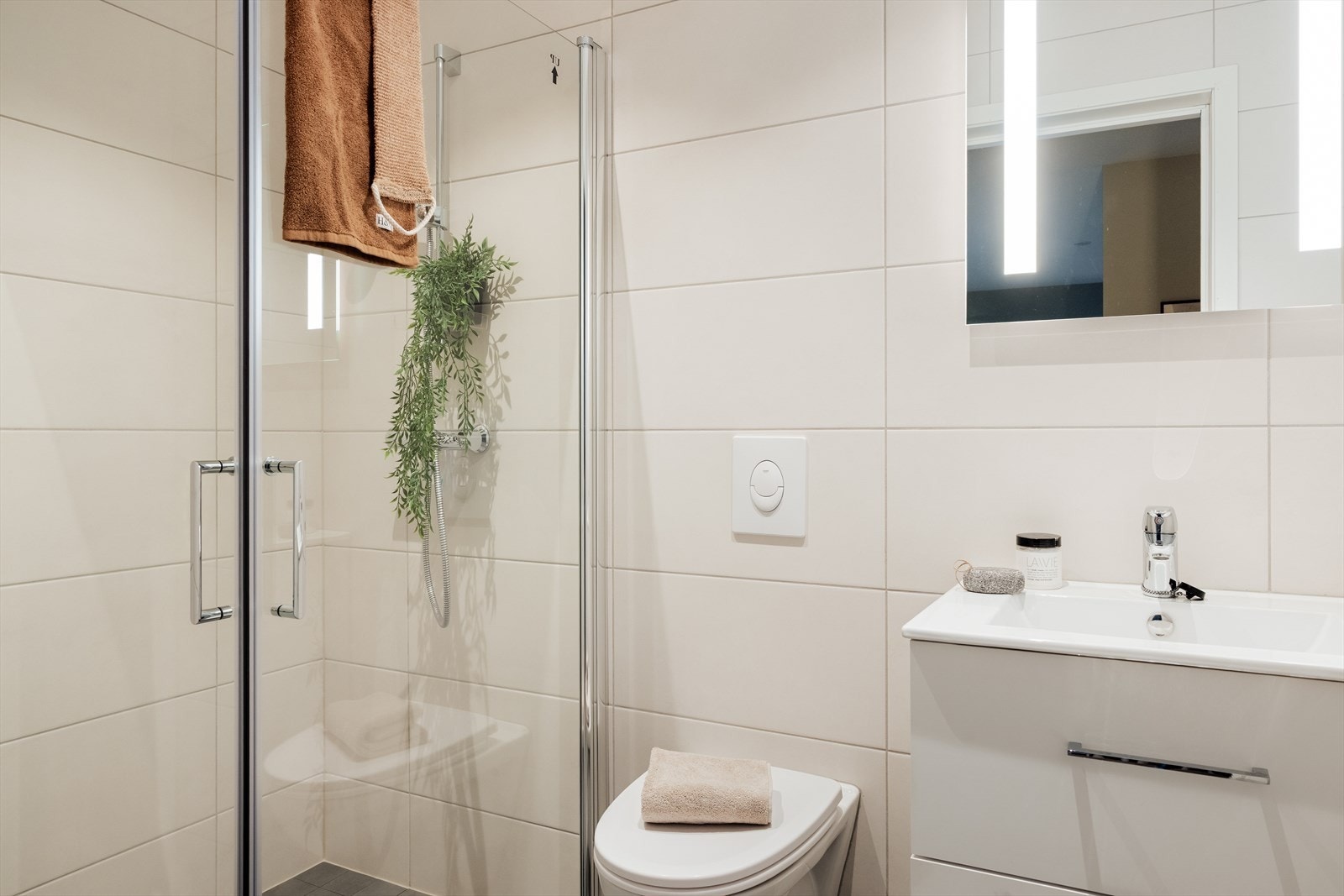 Bad nr. 2 holder en moderne standard med vegghengt toalett, helstøpt servant og dusj med klare glassdører Galleribilde