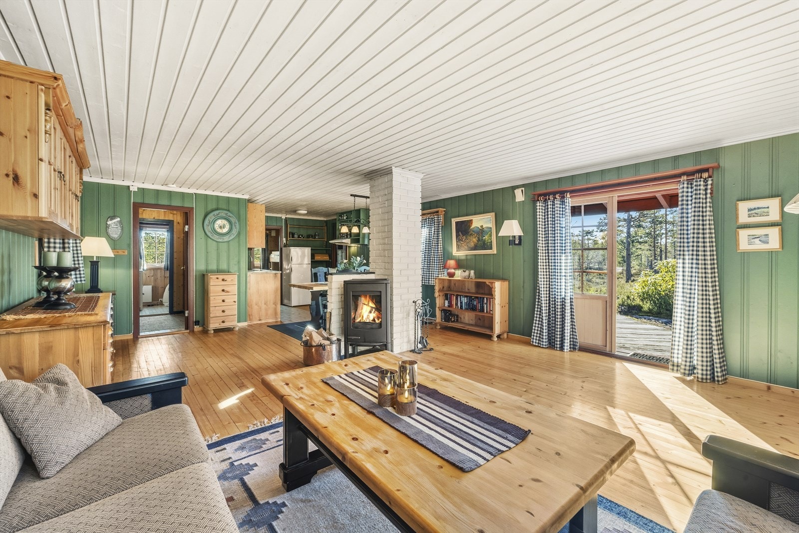 I stue er det tradisjonelt furugulv og malt panel på vegger og i himling. Galleribilde