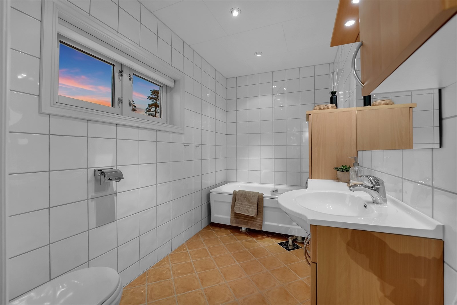 Badet er fra 2001 og har veggmontert toalett, badekar med dusjvegg i herdet glass samt baderomsinnredning med finerte fronter og heldekkende servant. Galleribilde