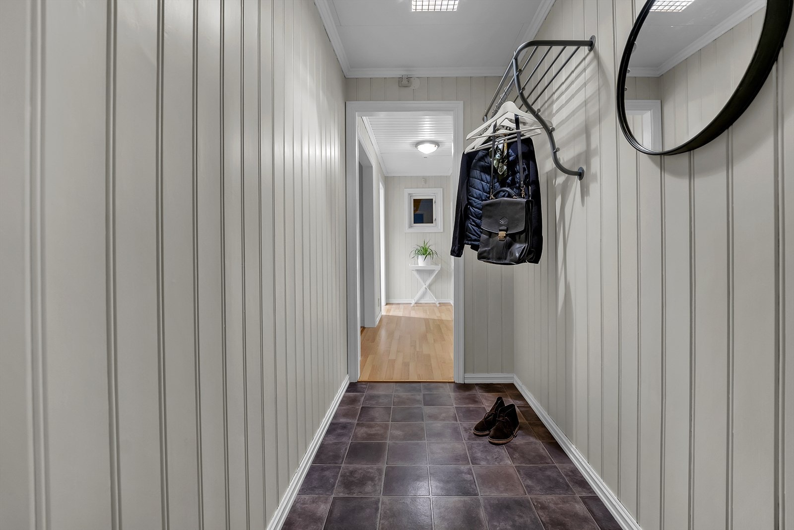 Velkommen inn i en praktisk og innbydende entré med vinylgulv. Her er det god plass til å henge fra seg yttertøy og sette fra seg sko, før man ledes videre inn i en større gang og resten av boligen. Galleribilde
