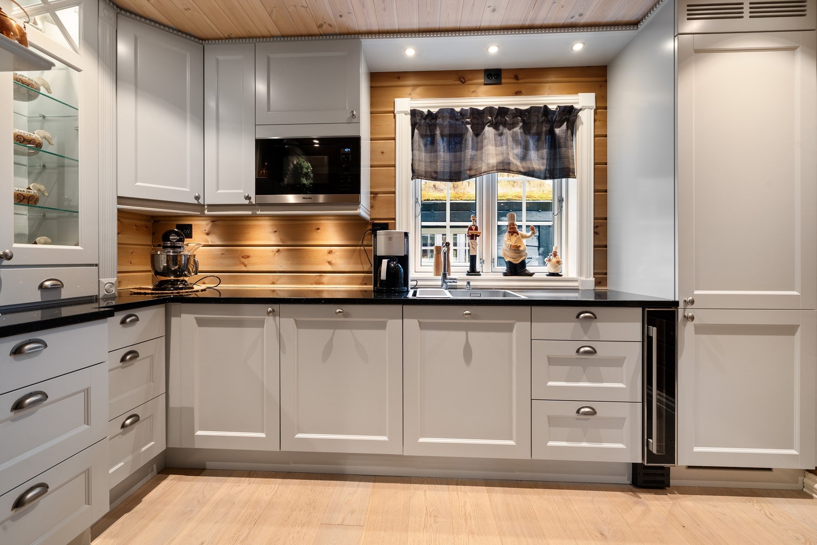 Lyst og trivelig kjøkken med benkeplate i stein, integrerer gode hvitevarer og vinskap. Galleribilde