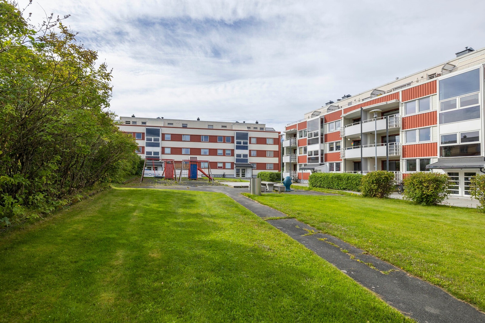 Fellesareal på baksiden av bygget. Bygget som leiligheten ligger i er til venstre i bildet, bak hekken. Galleribilde