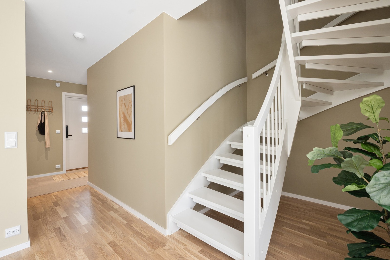 Trappen har åpne trinn, rekkverk med firkantede stolper, runde spiler og rektangulære håndløpere med avrundede kanter. Hele trappen er i kvistfrie materialer. Trinnene er parkettmønstret i hvitmalt furu Galleribilde