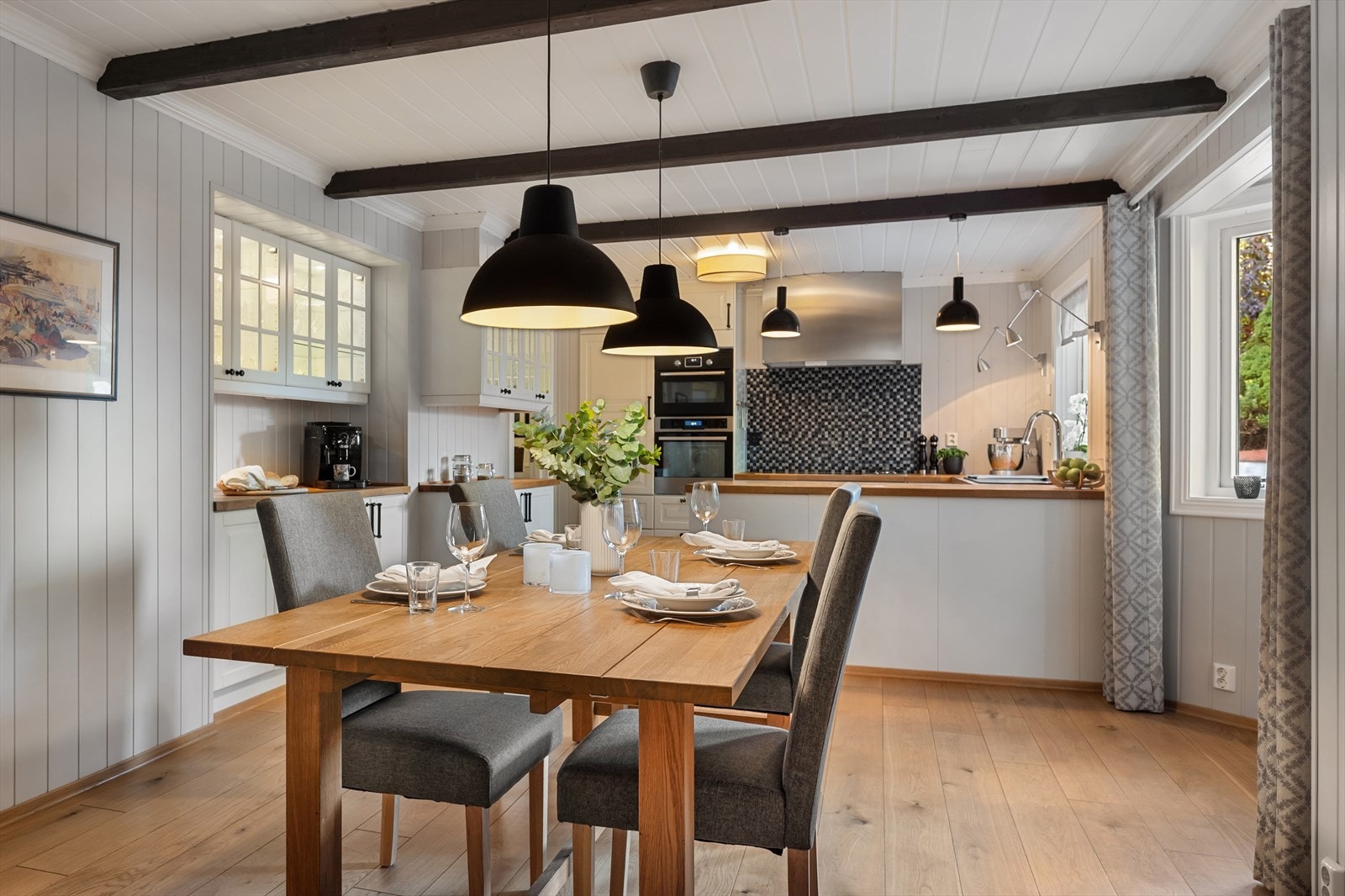 Det er åpen løsning mellom spisestue og kjøkken, noe som skaper en romslig og praktisk sone for både matlaging og måltider. Galleribilde