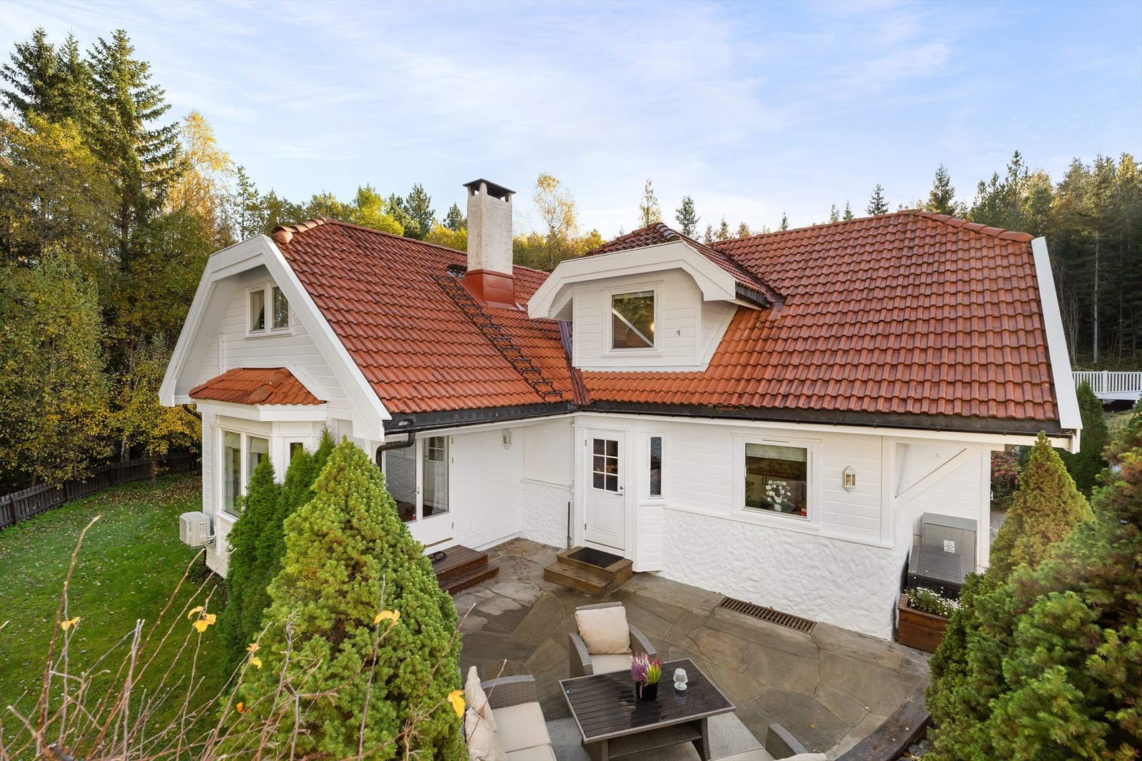 Tomten går over to nivåer og hagen er opparbeidet med plen, beplantning og gjerde mot skogen. Galleribilde