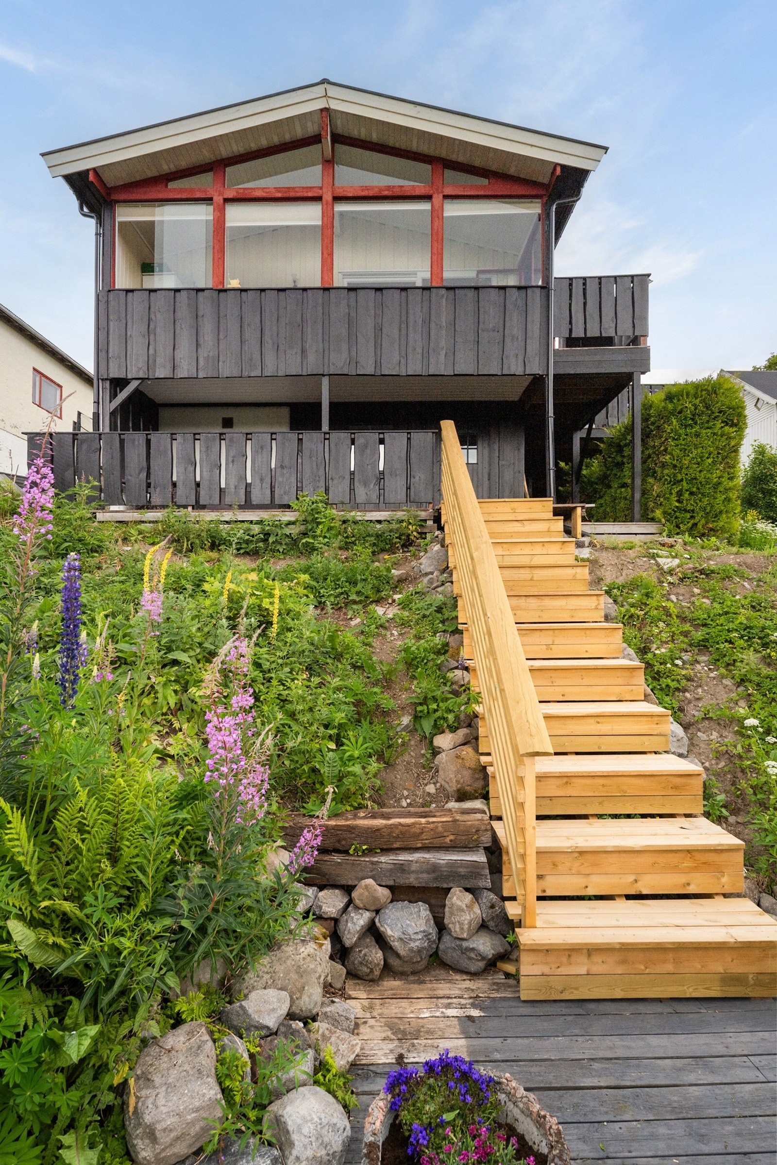 Tomten ligger i noe skrånende terreng. Trapp i treverk mellom nivåene. Galleribilde