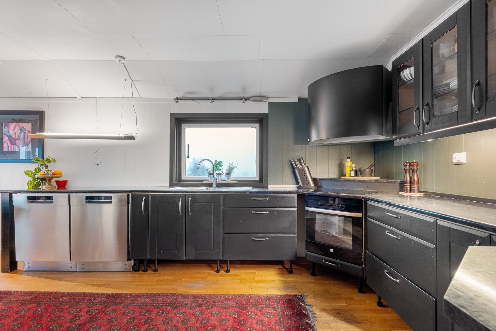 Flott kjøkken med innredning fra Mørekjøkken. Kjøkkenet har mye skap- og benkeplass, og flere skap har innfelt glass og downlights. Galleribilde