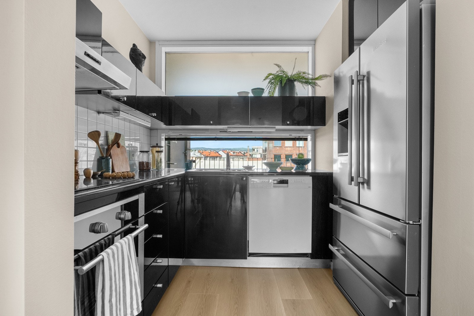 Pen kjøkkeninnredning med fliser og belysning over benkeplate i stein med oppvaskkum og 1-greps blandebatteri. Galleribilde