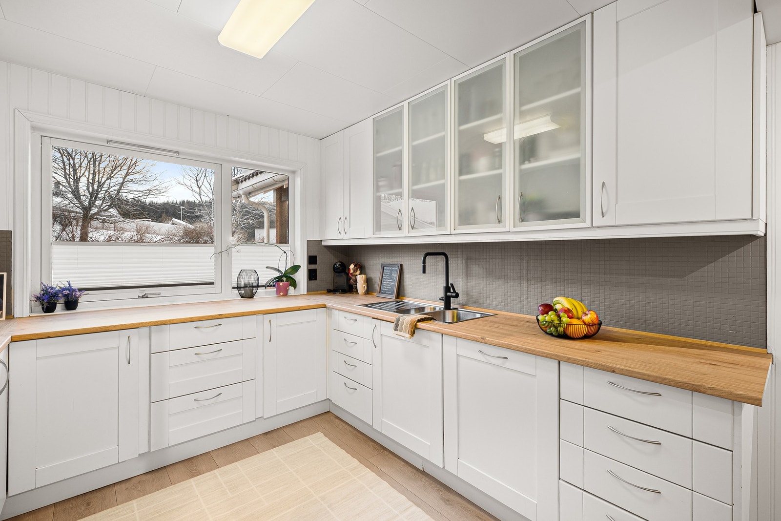 Pent og innbydende kjøkken med rikelig benkeplass og godt lys fra stort kjøkkenvindu. Galleribilde